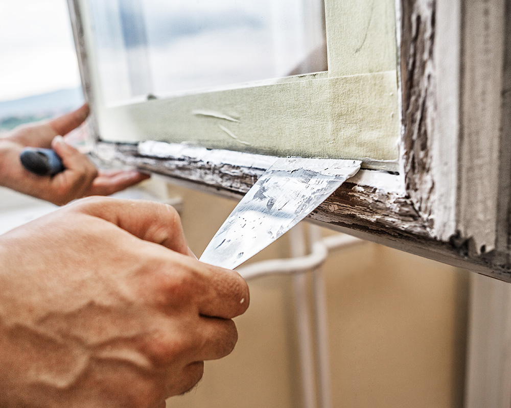 Man repairing wooden window frame seal